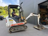 a man that is sitting in the back of a small excavator