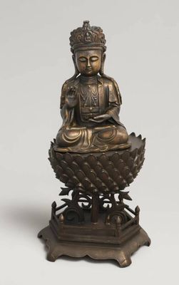 une statue en bronze représentant un Bouddha assis sur une fleur de lotus