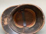 an old hat sitting on a table next to a cup