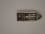 a metal object with a fish on it on a white surface