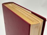 an open red book sitting on top of a table next to a white background