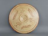 a brown plate with designs on it sitting on a table
