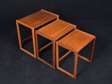 a set of three wooden nesting tables on a black background