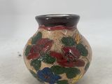 a small vase with flowers painted on it on a table