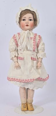 an antique doll with a white dress and bonnet is standing on a white surface