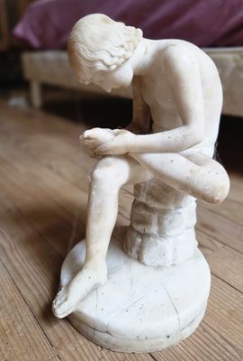 une petite statue représentant un homme assis sur un tabouret