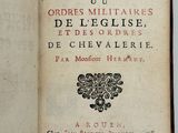 un livre ouvert posé sur une table blanche, dont la couverture porte un titre en noir et rouge