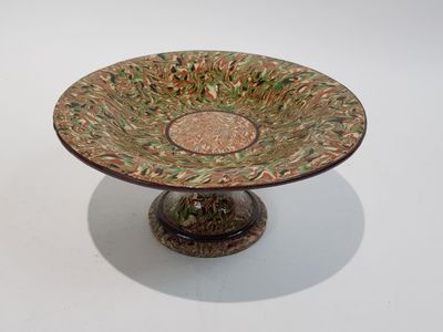 une assiette verte et marron posée sur un socle