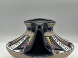 a black and blue vase sitting on a white surface