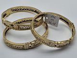 trois bracelets rigides en or ornés de motifs gravés et d'une étiquette de prix