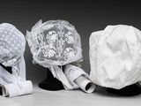 trois chapeaux sont alignés sur la tête d'un mannequin