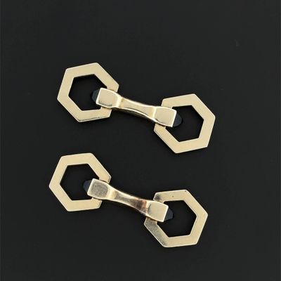 pair of brass plated hexagonal clips on a black background