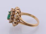 a close up of a gold ring with a green stone