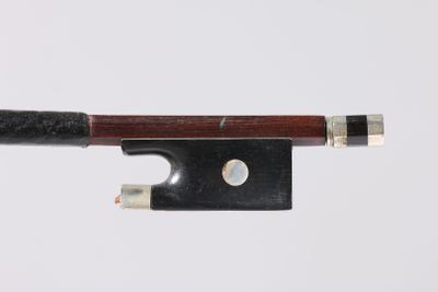 un gros plan d'un archet de violon posé sur une surface blanche