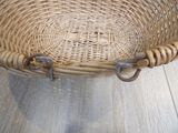 a wicker basket with a metal handle on the floor