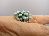 Quelqu'un tient une bague sertie de pierres de turquoise.