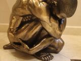une statue en bronze représentant un homme assis par terre