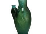 a green vase with a hand holding a blue glass