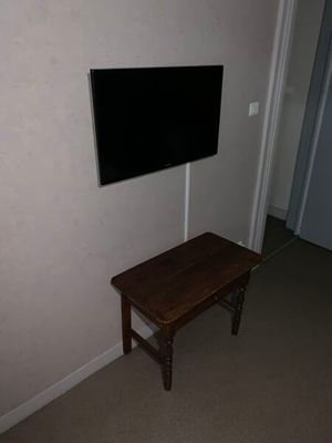 une petite table sur laquelle est posée une télévision, dans un coin de la pièce