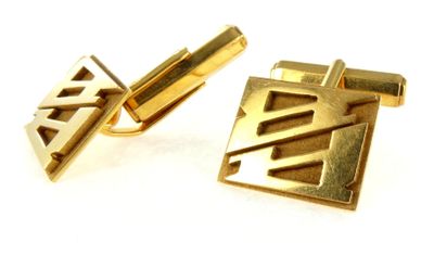 two gold cufflinks on a white surface with a white background