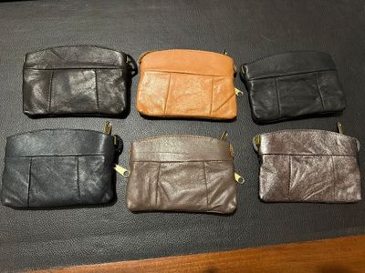 several different types of leather purses lined up on a table