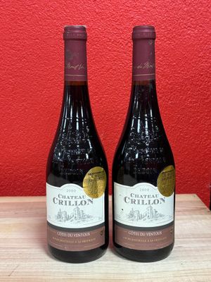 two bottles of wine sit on a table in front of a red wall