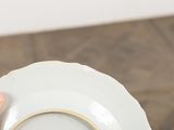 a person holding a white plate with a gold rim
