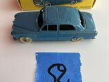 une petite voiture bleue posée à côté d'une boîte de Dinky Toys