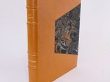 an orange book sitting on top of a white table next to a white wall