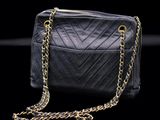 a black purse with gold chains on a black background
