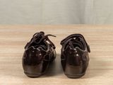pair of brown shoes on a wooden table with a curtain in the background