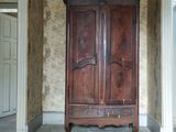 une vieille armoire en bois dans une pièce dont l'un des murs est tapissé