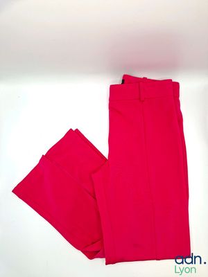 un pantalon rose posé sur une surface blanche, avec un fond blanc