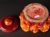 a red vase and a red lid on a black surface