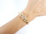 wrist shot of a woman wearing a gold watch and bracelet