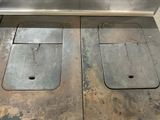 two metal sinks in the middle of a dirty floor