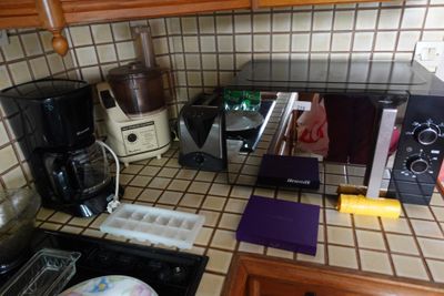 un plan de travail de cuisine équipé d'un micro-ondes, d'un grille-pain, d'une cafetière et d'autres ustensiles de cuisine