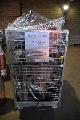 un homme debout à côté d'une cage métallique sur laquelle est accrochée une pancarte