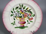 une image représentant une assiette rose et blanche ornée d'un oiseau et de fleurs