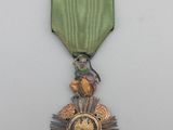 une image représentant une médaille ornée d'un ruban vert et d'un oiseau