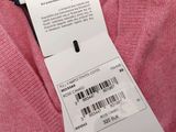 the label of a pink sweater is attached to a pink jacket