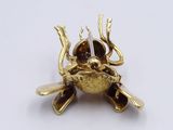 a gold frog brooch with a candle in it ' s mouth