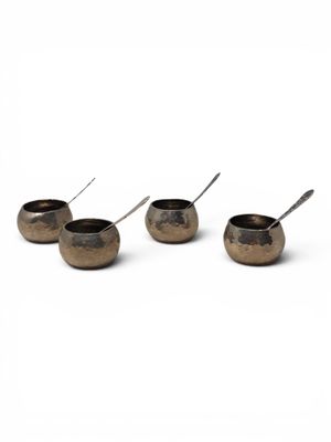 four small bowls with spoons are lined up on a white surface