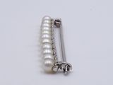 a white pearl and silver pin on a white surface