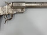 un revolver en argent avec une poignée en bois sur une surface blanche