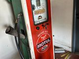 a red and green gas pump next to a white wall