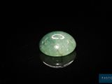 boule de jade verte posée sur une surface noire, avec un fond noir