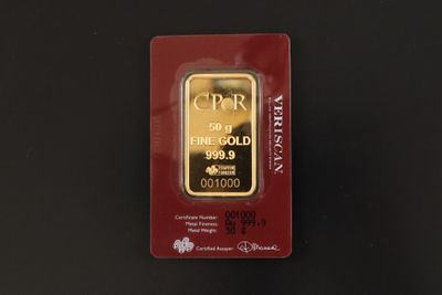 un lingot d'or dans un emballage rouge posé sur une surface noire