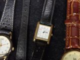 several different watches are displayed in a display case on a black surface