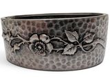 a close up of a metal bracelet with flowers on it